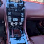 鮮やかな本革赤レザーと高級感あるセンターコンソール。オートエアコン、パワーシート完備のアストンマーチン DB9内装。