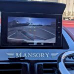 MANSORY（マンソリー）ロゴが映える内装パネル。バックモニターカメラとBluetooth対応ナビを装備したアストンマーチン DB9。